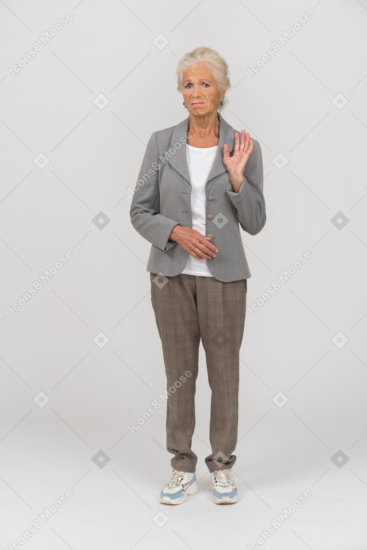 Front view of an upset old lady standing with raised hand