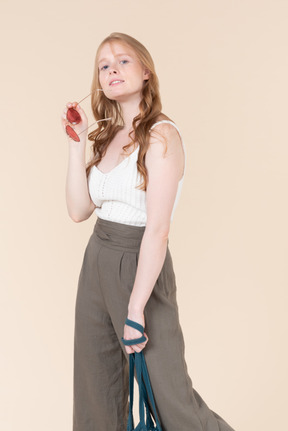 A woman is holding a blue bag and posing for a picture