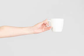 Female hand holding white ceramic cup