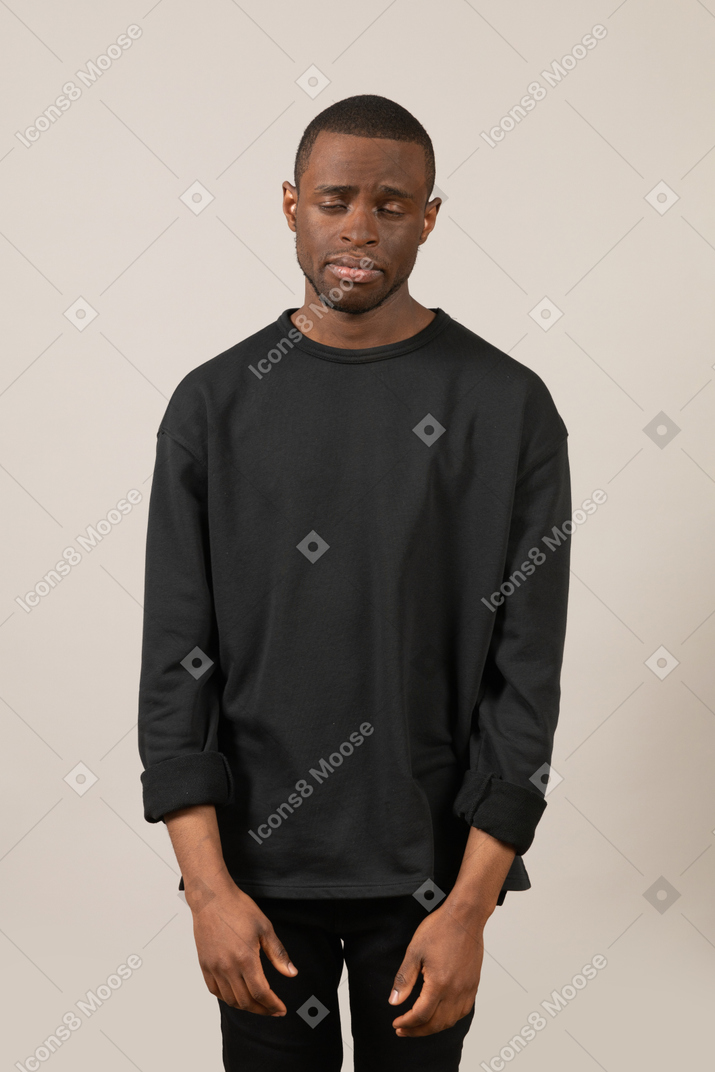 Sad young man standing with closed eyes