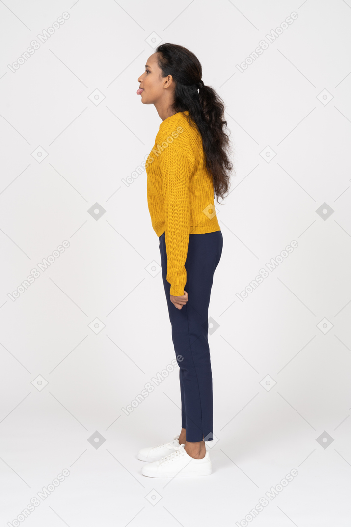 Girl in casual clothes standing in profile and showing tongue