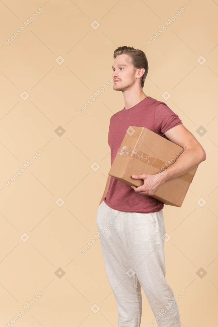 Delivery guy standing with his hand in the pocket and holding a parcel