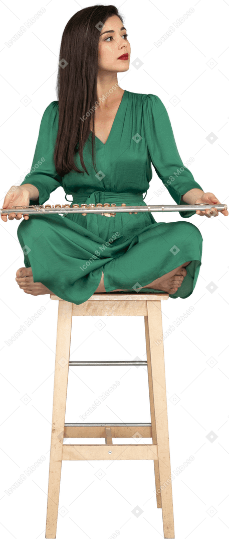In voller länge einer jungen dame, die ihre klarinette auf den knien hält, während sie auf einem holzstuhl sitzt