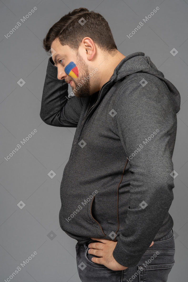 Side view of a tired male football fan touching head