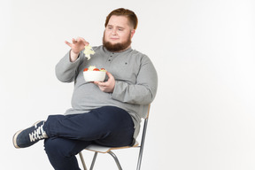 Bid bearded guy picked up salad leaf from the plate