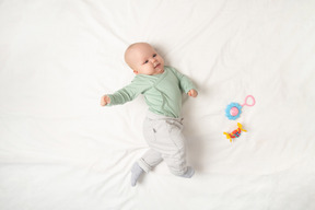 Baby girl lying on the back near toys