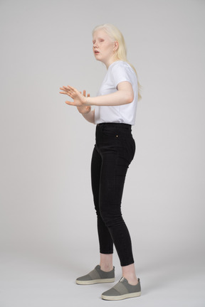 Vista de tres cuartos de una niña extendiendo los brazos