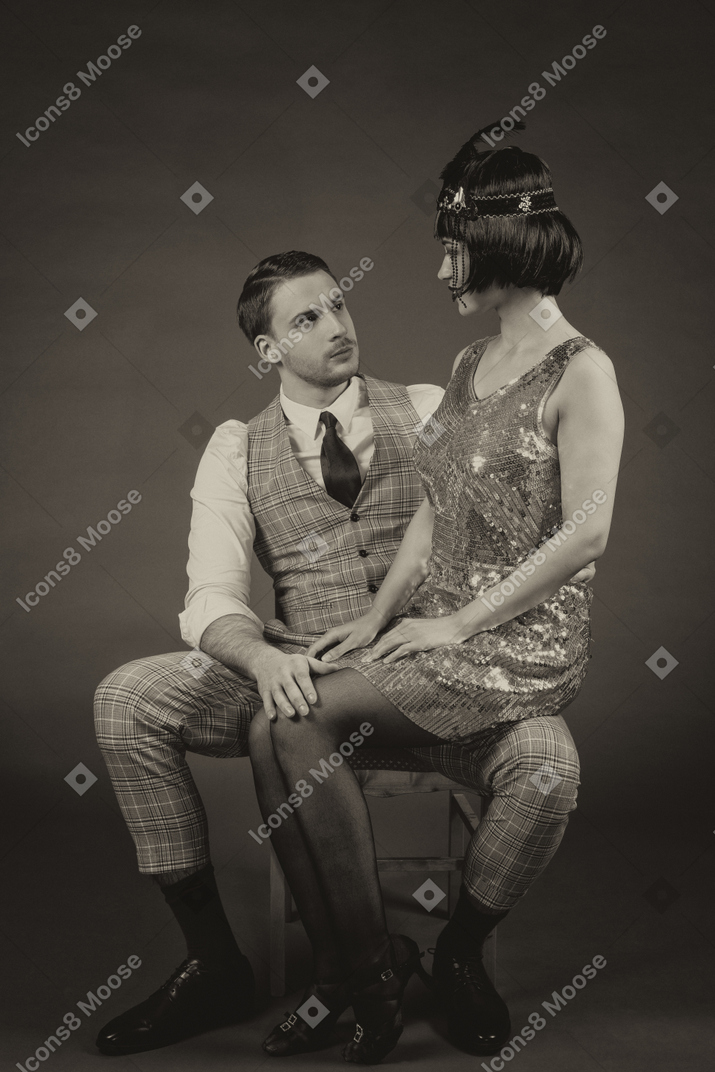 Retro-styled portrait of a beautiful lady sitting on gentleman`s knees