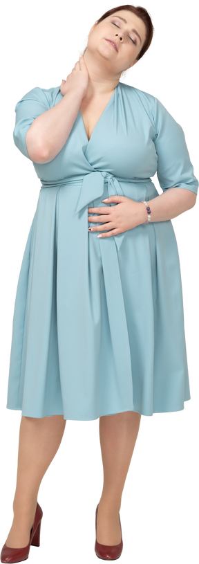 Vista frontal de una mujer en vestido azul que sufre de dolor en el cuello