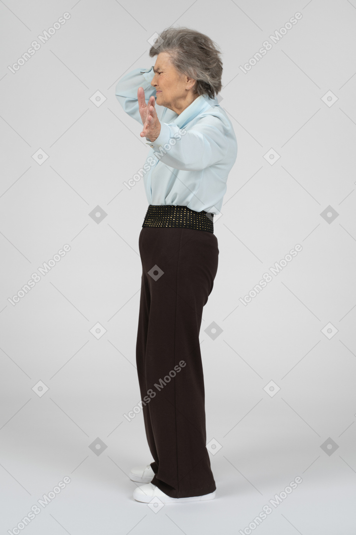 Old woman with headache stretching out hand to camera