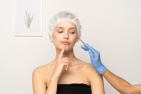 Surgeon holding scalpel near female patient's face