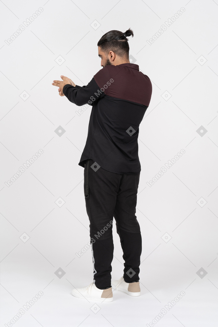 Young man with a bun aiming with finger gun