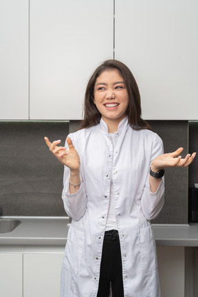 Front view of a female doctor smiling and gesticulating while looking aside