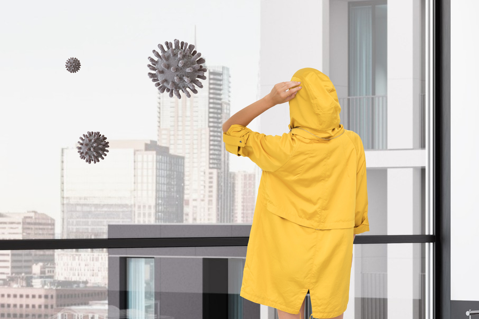 Young man in a yellow raincoat standing near the window in the office