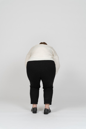 Rear view of a plump woman in white sweater bending down