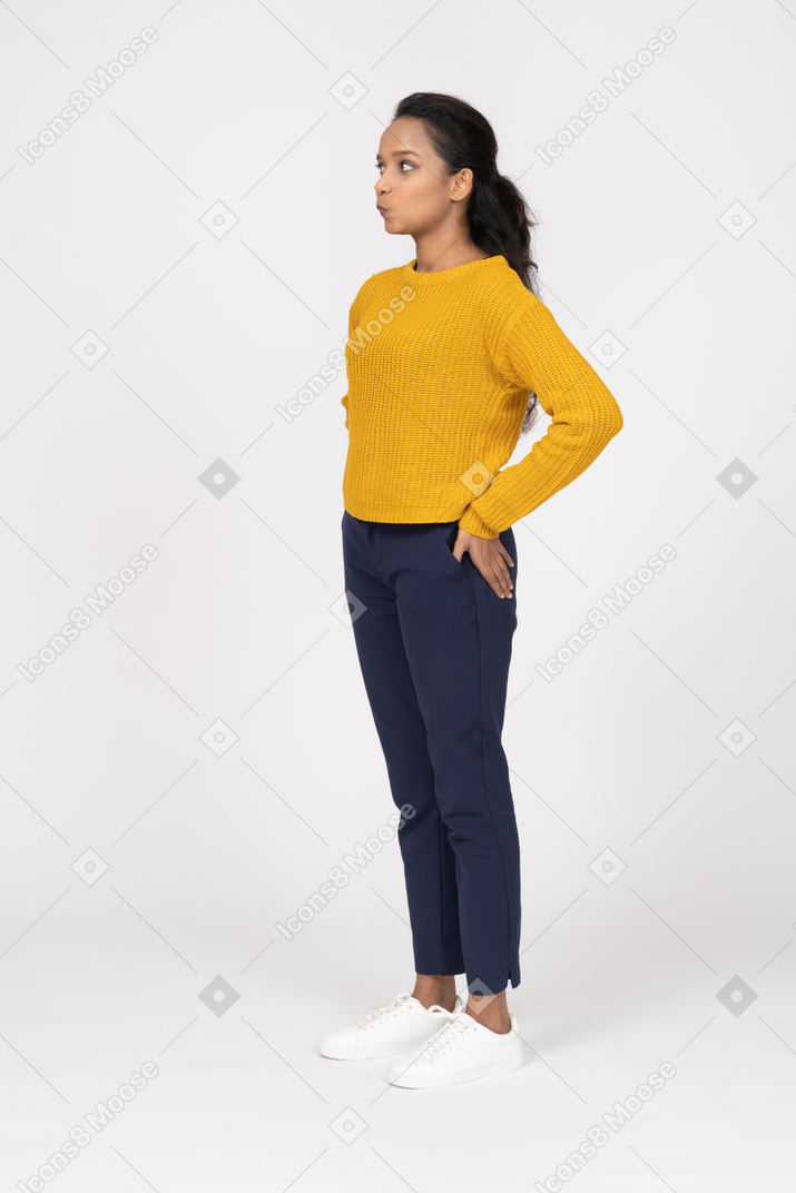 Side view of a girl in casual clothes standing with hand on hip and pouting lips