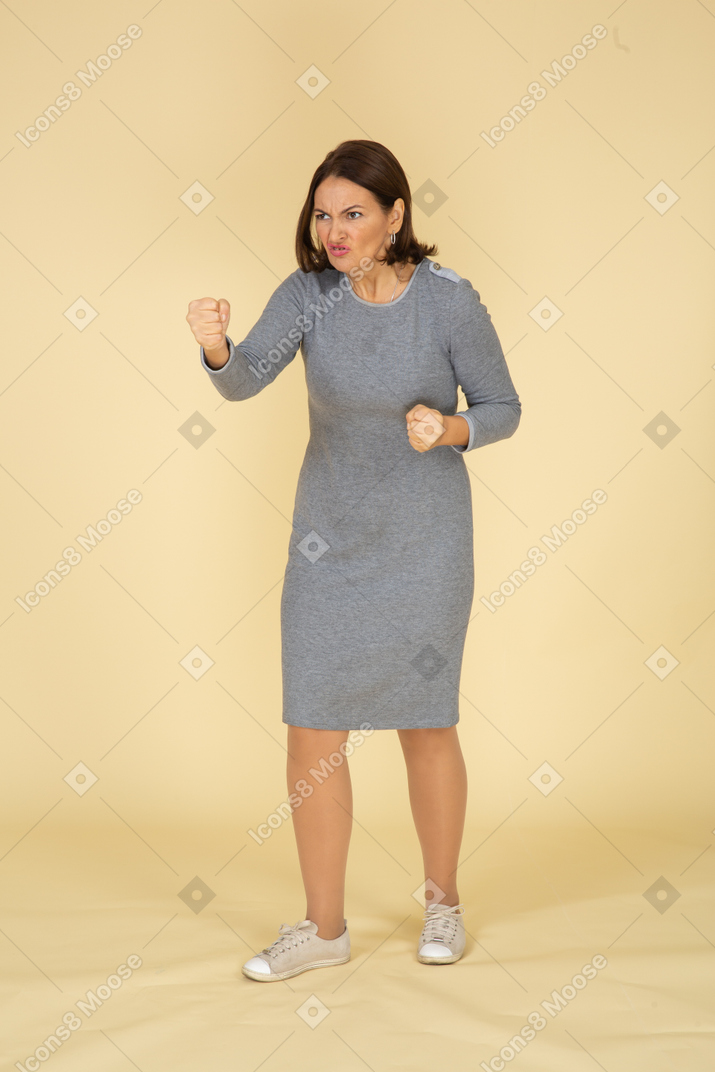 Vista frontale di una donna arrabbiata in abito grigio