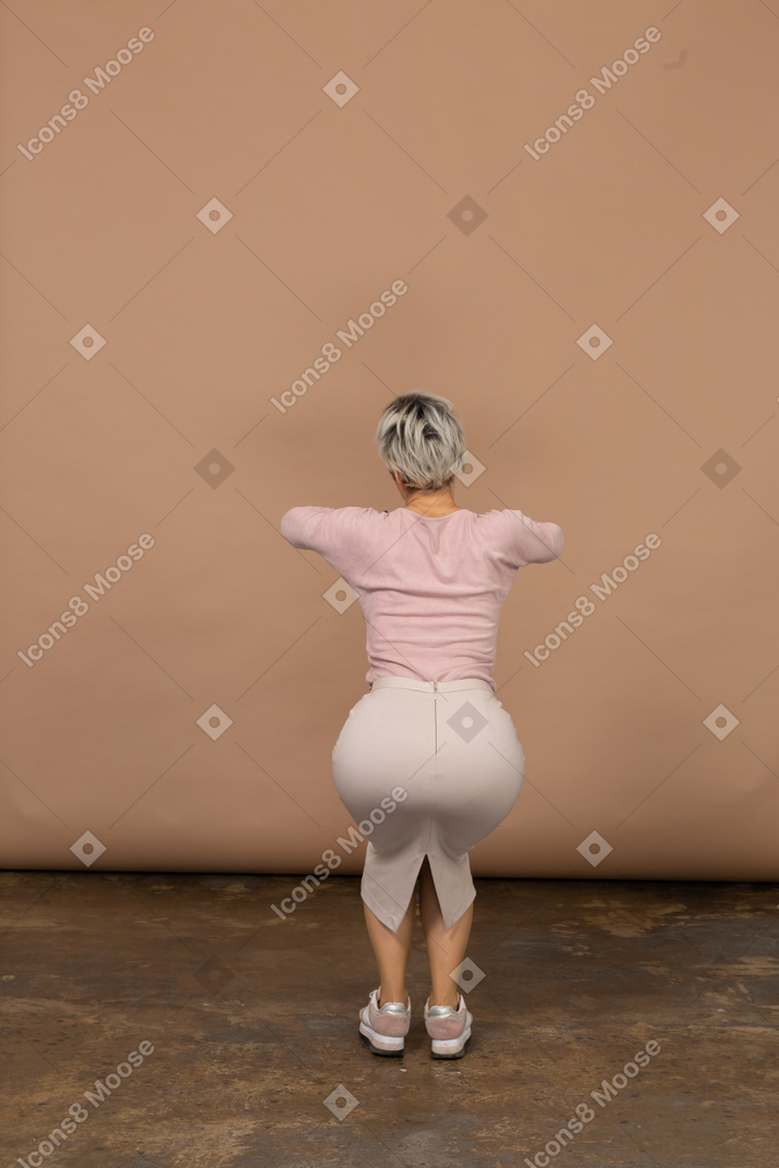 Rear view of a woman in casual clothes squatting