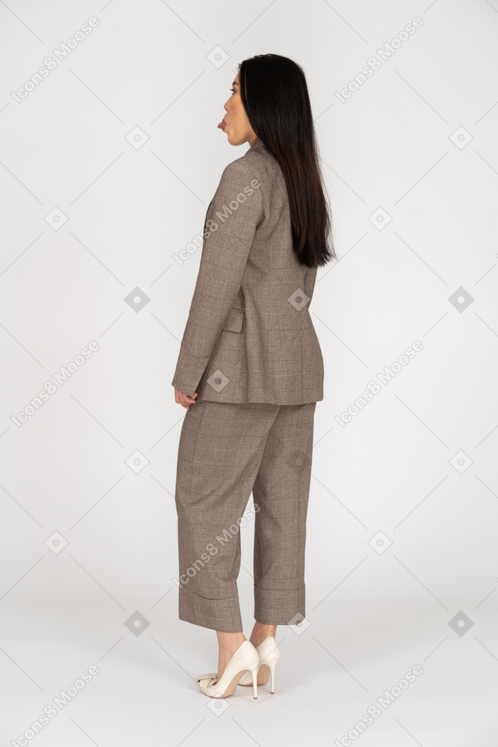 舌を示す茶色のビジネススーツの若い女性の4分の3の背面図