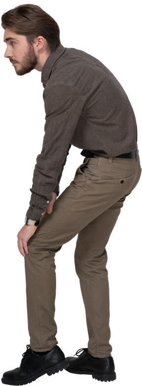 Vue latérale d'un jeune homme en vêtements de bureau touchant le genou