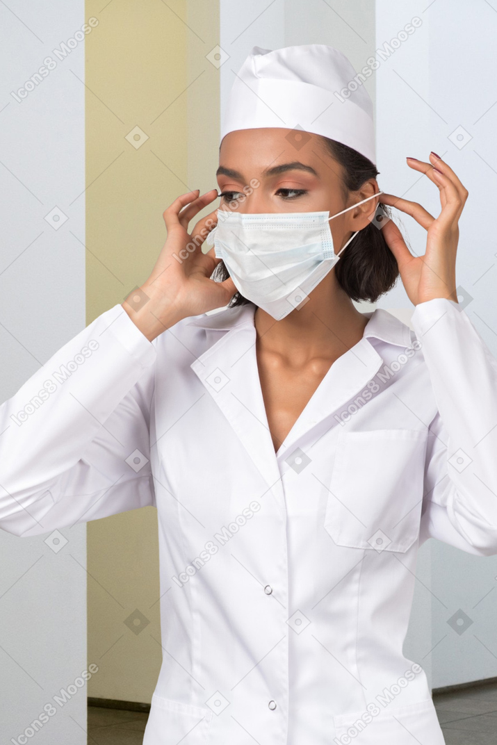 A woman in a white lab coat and surgical mask