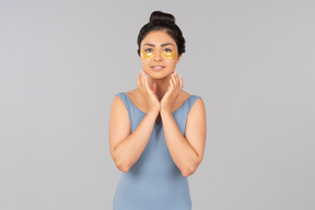 Indian woman with eye patches touching her face with hands