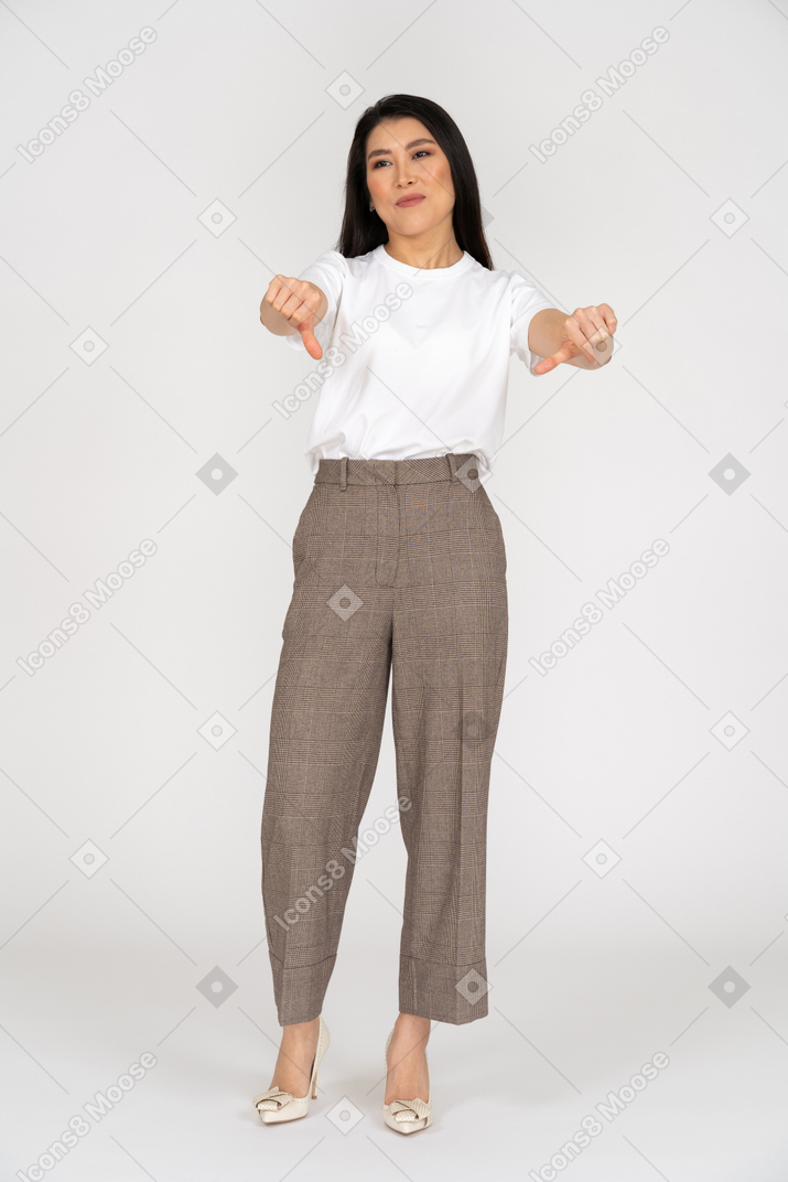 一位年轻的女士，穿着马裤和t恤，大拇指朝下的前视图