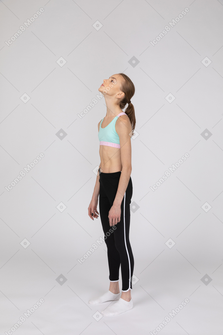 Vue latérale d'une adolescente en tenue de sport en levant la main et en faisant valoir