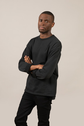 Three-quarter view of young man standing with arms crossed