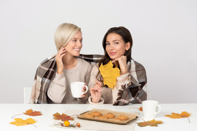 Mujeres jóvenes bebiendo café y comiendo galletas en otoño