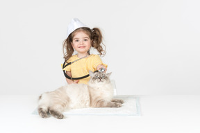 Little kid girl with stethoscope and wearing medical hat curing a cat