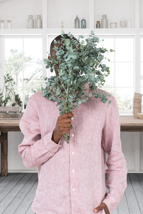 A man in a pink shirt is holding a plant