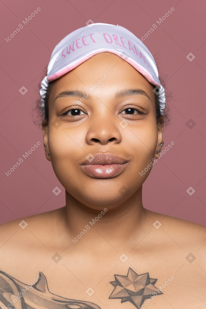 Mulher afro encantada na máscara de dormir de frente para a câmera