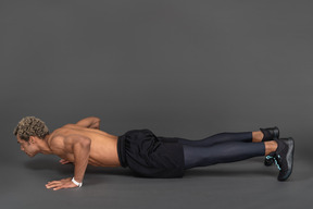 Side view of a shirtless afro man making push-ups