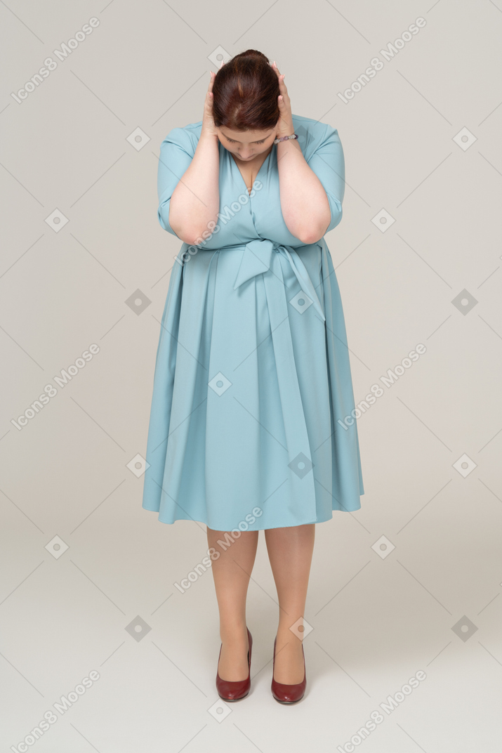 Vista frontale di una donna in abito blu che soffre di dolore al collo
