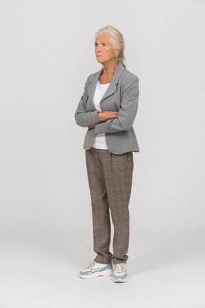 Front view of an old woman in suit posing with crossed arms