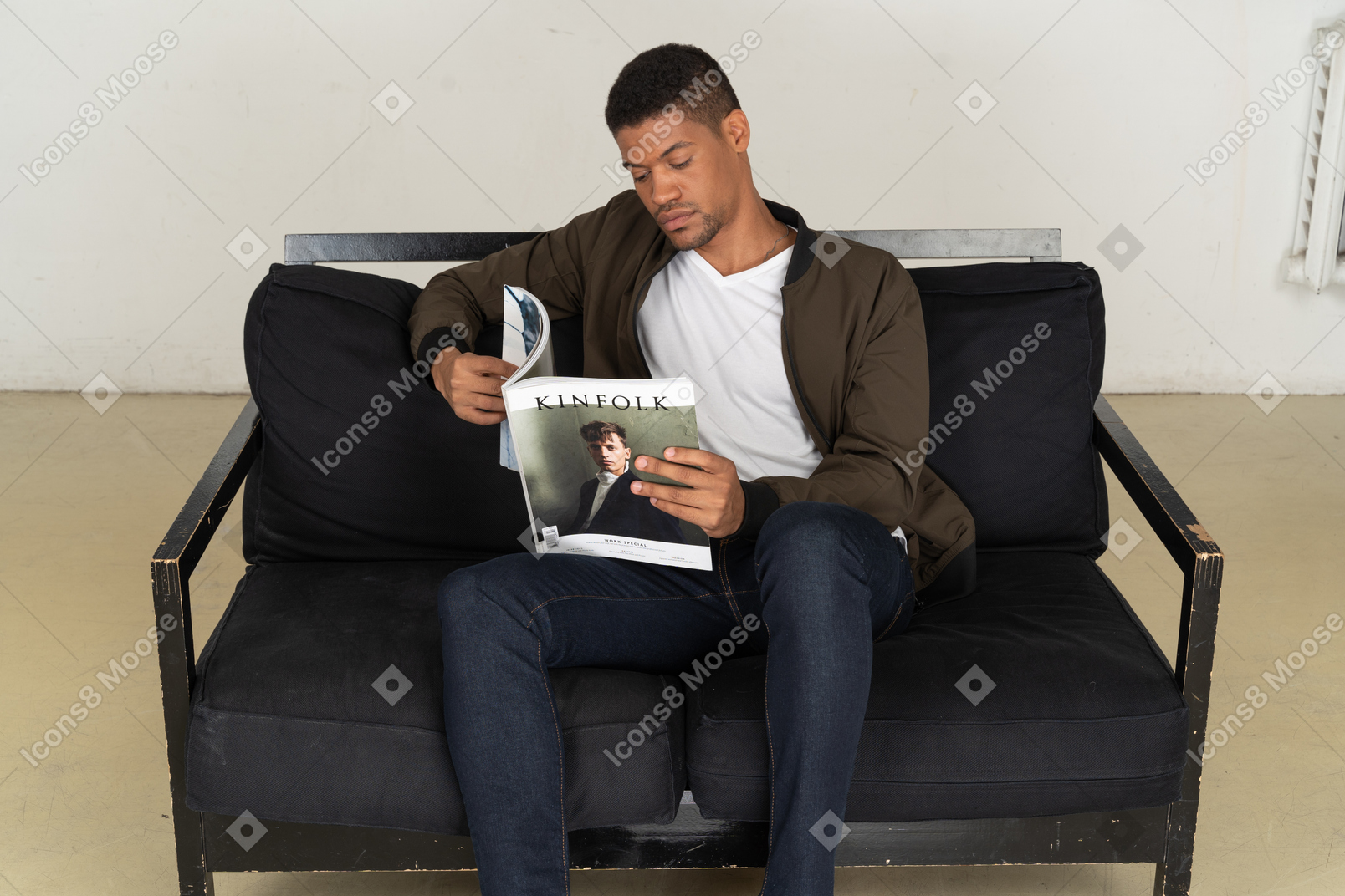 ソファに座って雑誌を持っている美しい若い男