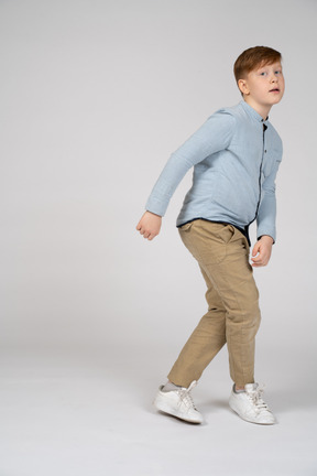 A boy standing and crossing legs