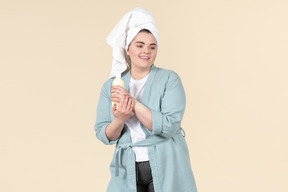 Junges plus-size mädchen in einem blauen bademantel, der um ihrer haut nach einer dusche sich kümmert