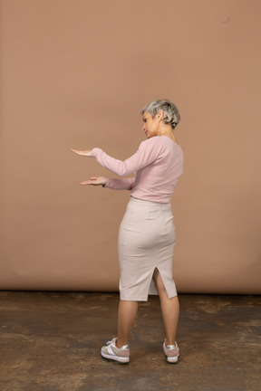 Rear view of a woman in casual clothes showing the size of something