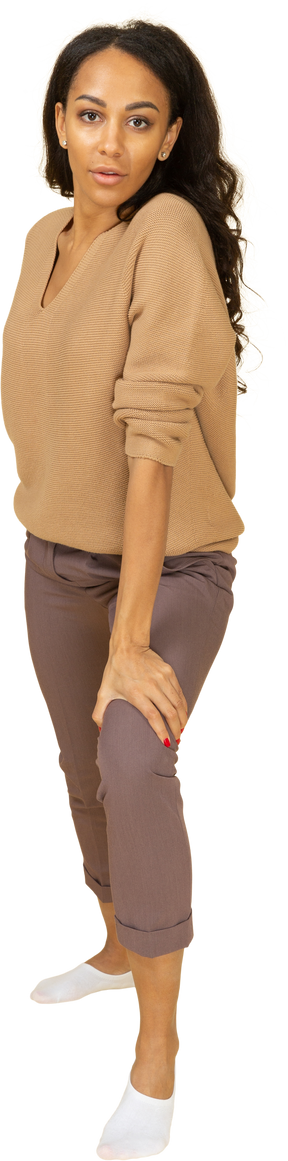 Vista frontal de una mujer joven de piel oscura apoyada en su pierna