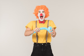 Excited looking male clown holding blue balloon