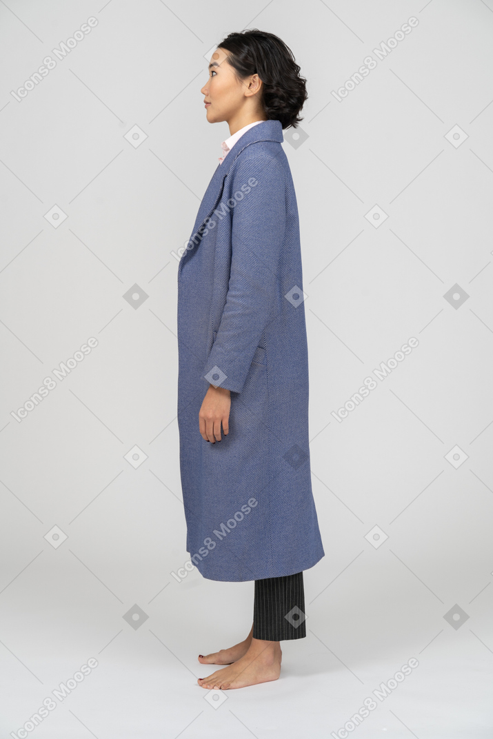 Vista laterale di una donna dagli occhi spalancati in cappotto blu