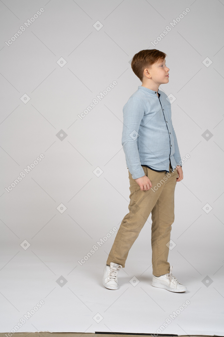 Vista lateral de um menino em pé olhando para a frente