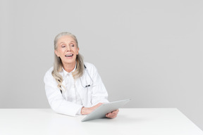 Aged female doctor working on a digital tablet