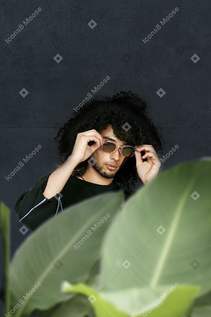 Young curly man adjusting his sunglasses