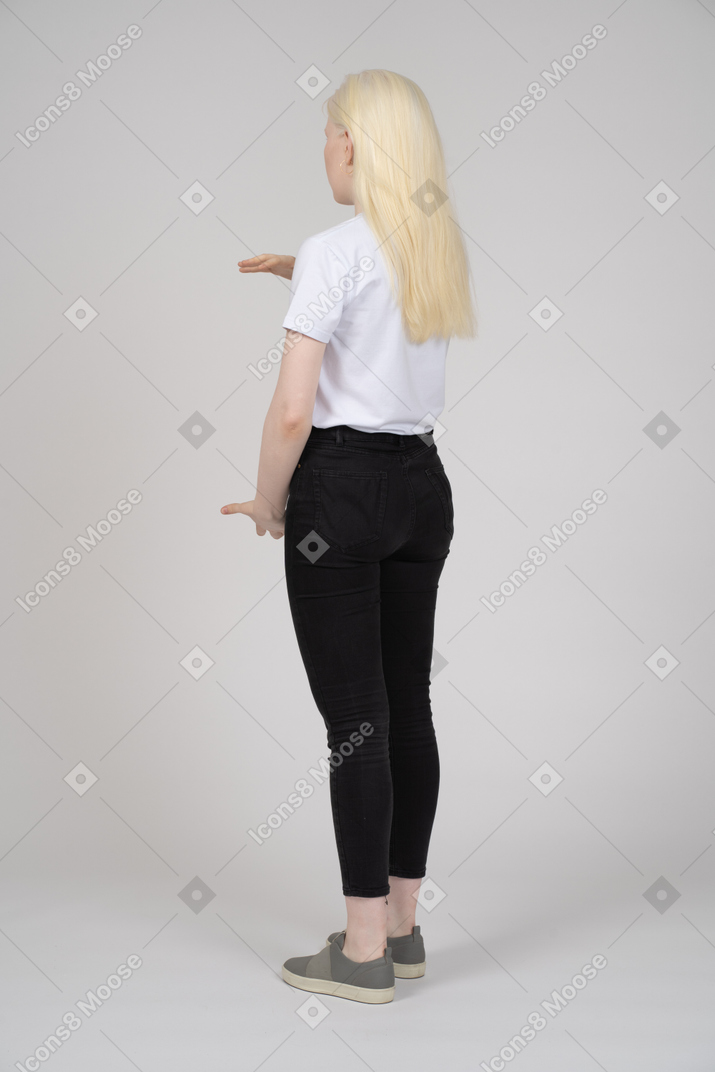 Vista posteriore di una donna bionda che mostra le dimensioni di qualcosa di grande