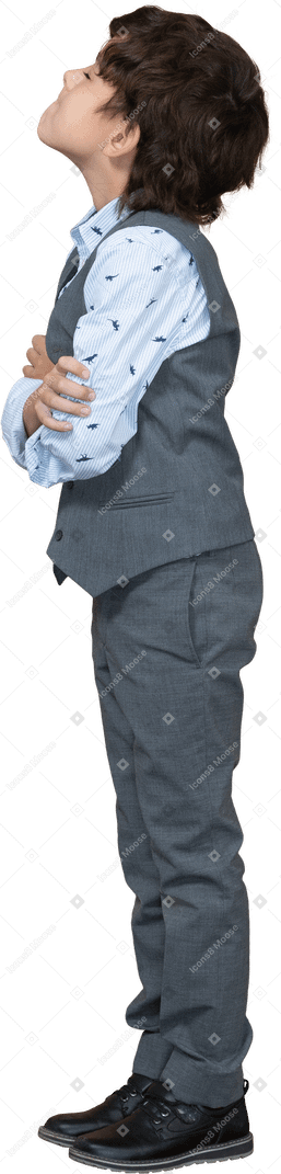 Vue latérale d'un garçon en costume debout avec les bras croisés