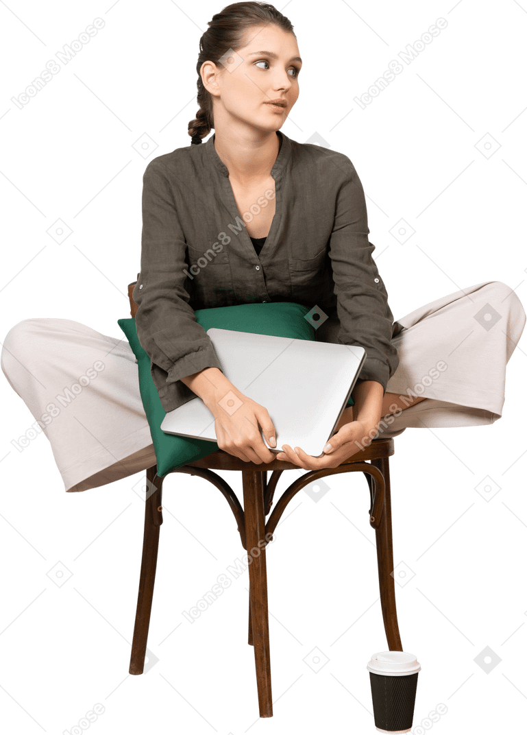 Front view of a bored young woman sitting on a chair and holding her laptop