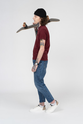 A teenager walking with his skateboard